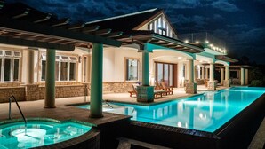 Un'area piscina con vasca idromassaggio, posti a sedere all'aperto e un portico coperto.