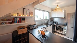 Una cocina moderna con encimera negra, electrodomésticos de acero inoxidable y una ventana que proporciona luz natural.