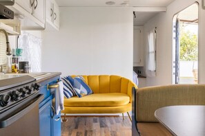 Une cuisine de taille réduite, équipée d’une cuisinière, avec un canapé jaune et un coin repas.