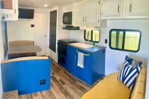 A compact RV interior with a kitchenette, a dining area, and a sleeping space. - El Camper - Your Cozy Retreat in Aguadilla (Aguadilla Pueblo)
