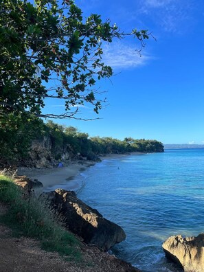 A coastal landscape with a clear sky, a sandy beach, and rocky outcrops. - El Camper - Your Cozy Retreat in Aguadilla (Aguadilla Pueblo)