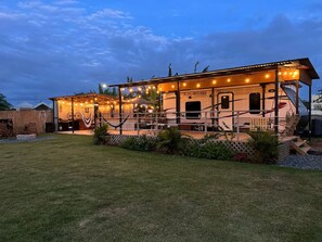 A well-lit, spacious RV with a covered outdoor area, including a barbecue grill and seating.