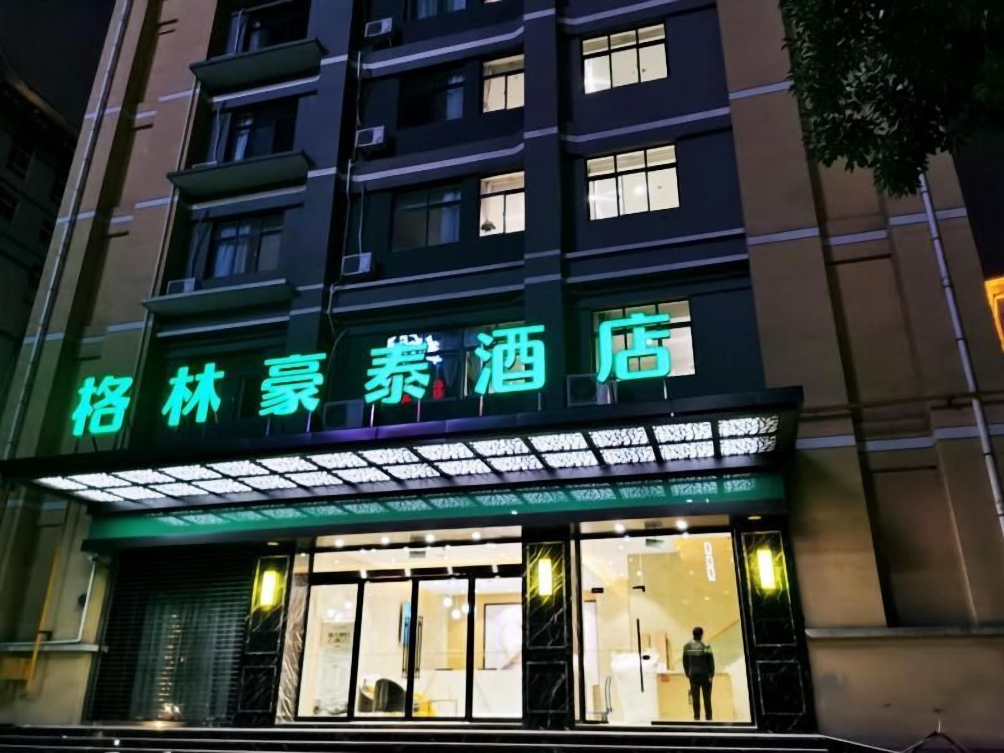 A hotel with a neon sign, large windows, and a visible entrance.