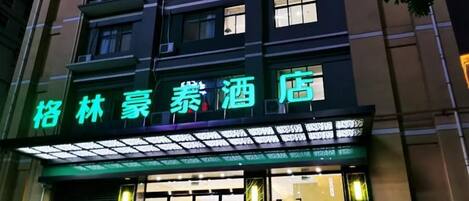 A hotel with a neon sign, large windows, and a visible entrance.