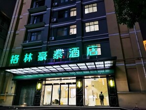 A hotel with a neon sign, large windows, and a visible entrance. - Greentree Inn Ankang Middle Bashan Road Business Hotel (Ankang)