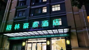 A hotel with a neon sign, large windows, and a visible entrance.