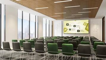 A conference room with rows of chairs, a presentation screen, and large windows.