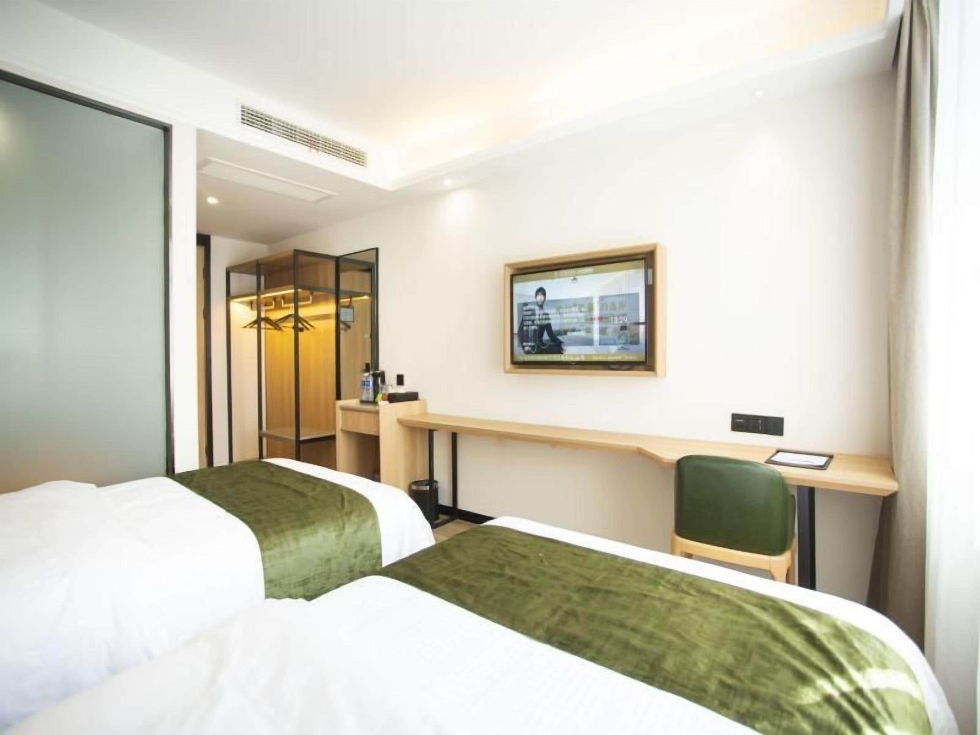Una camera d'albergo con due letti, una scrivania, una sedia, uno specchio e un quadro appeso al muro.