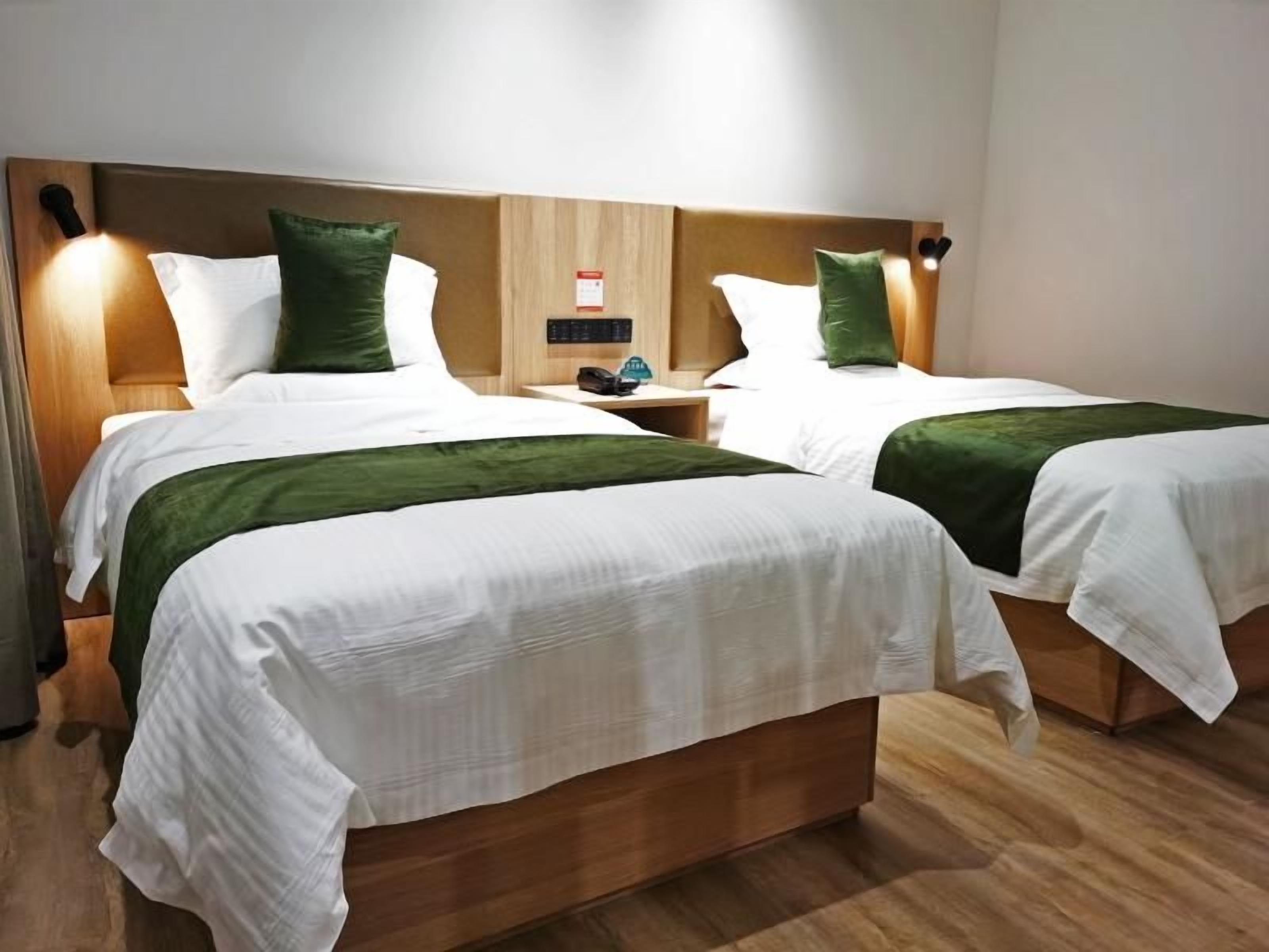 A hotel room with two beds, wooden headboards, and bedside tables with lamps.