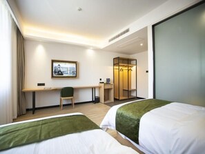 A hotel room with two beds, a desk, a chair, a wardrobe, and a framed picture on the wall. - Greentree Inn Ankang Middle Bashan Road Business Hotel (Ankang)