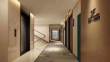 A modern hotel corridor with a carpeted floor, a staircase, and a wooden wall with a sign.