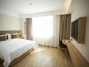 A hotel room with a large bed, a desk, and a window with curtains. - Greentree Inn Ankang Middle Bashan Road Business Hotel (Ankang)