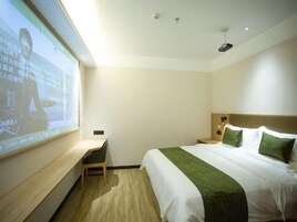 Habitación de hotel con cama, escritorio y pantalla proyectando una presentación.