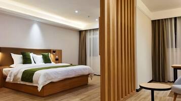 Habitación de hotel con una cama de madera, una pequeña mesa redonda y una pared divisoria.