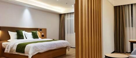 Habitación de hotel con una cama de madera, una pequeña mesa redonda y una pared divisoria.