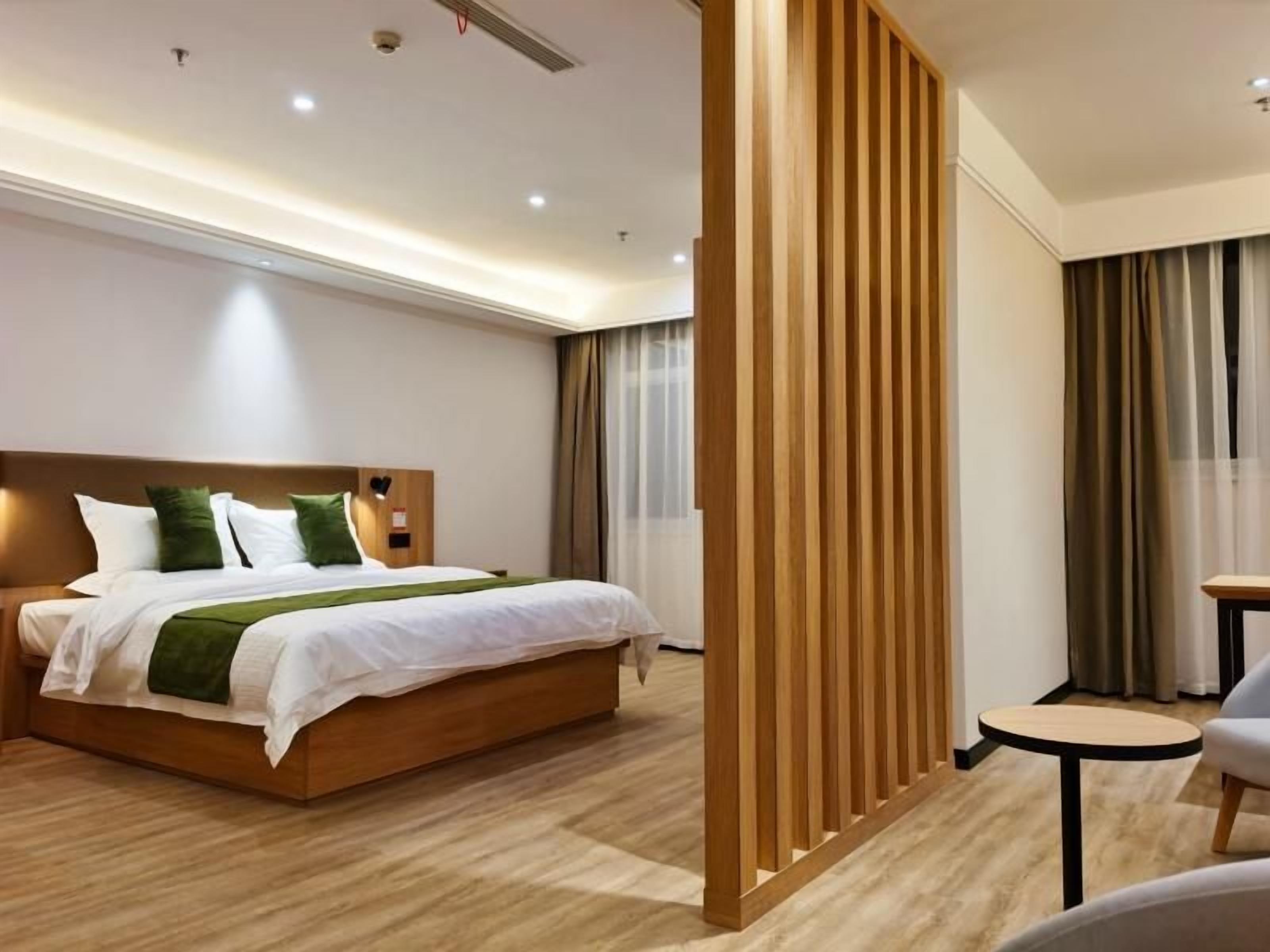 Habitación de hotel con una cama de madera, una pequeña mesa redonda y una pared divisoria.