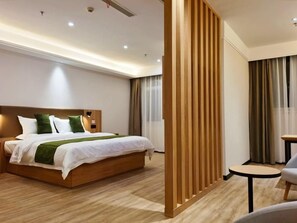 Ein Hotelzimmer mit einem hölzernen Bett, einem kleinen runden Tisch und einer Raumtrennwand.