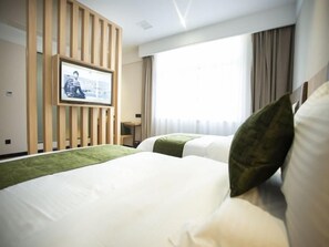 A hotel room with a large bed, a TV mounted on a wooden panel, a small table, and a window with curtains. - Greentree Inn Ankang Middle Bashan Road Business Hotel (Ankang)