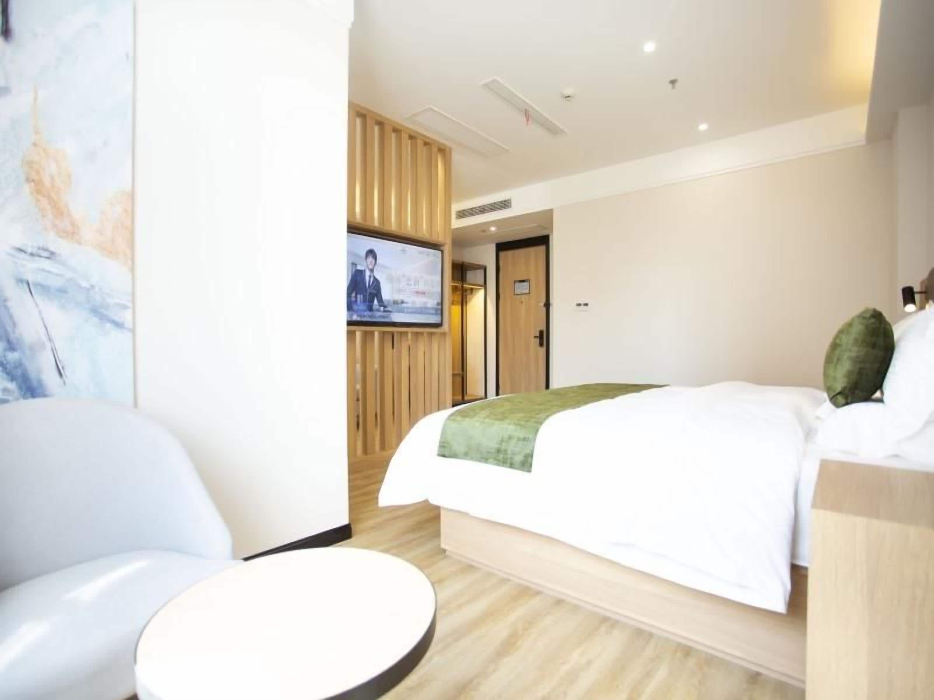A hotel room with a bed, a television, a seating area, and a wooden panel wall.