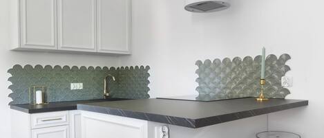 Una cocina moderna con armarios blancos, encimera de mármol y un original salpicadero verde.