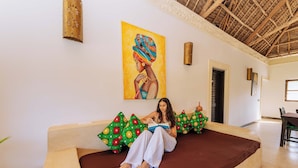 A room with a bed, a painting, and a dining area. - 6-BEDROOMS POOL VILLA in JAMBIANI (Zanzibar east coast)