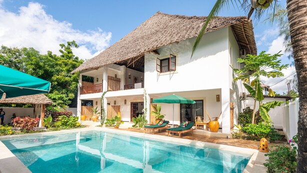 A two-story building with a pool, outdoor seating, and tropical plants. - 6-BEDROOMS POOL VILLA in JAMBIANI (Zanzibar east coast)