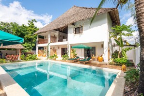 A two-story building with a pool, outdoor seating, and tropical plants. - 6-BEDROOMS POOL VILLA in JAMBIANI (Zanzibar east coast)