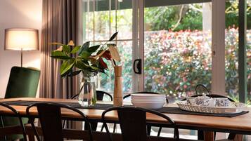 Une table à manger avec des chaises, un vase avec une plante, un pichet et un plateau avec des tasses et des soucoupes à thé.