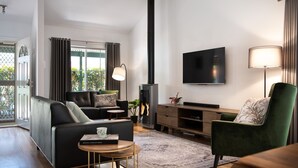 Una sala de estar moderna con sofá, sillón, televisión, chimenea y un comedor con mesa y sillas.