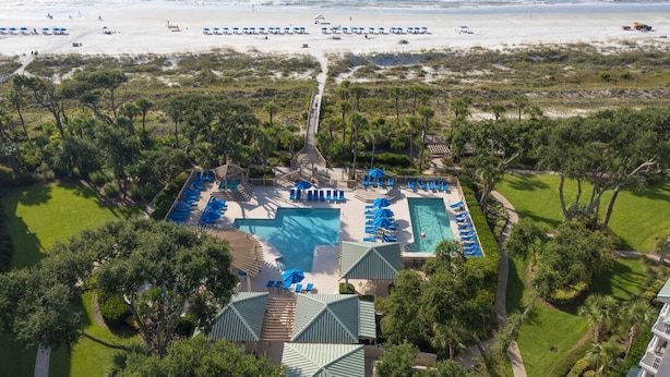 Un resort con una grande piscina, numerosi lettini e vista sulla spiaggia.