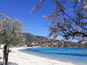 A beach with clear blue water, a sandy shore, and a town in the background. - LUXURY APARTMENT - 4-BEDROOM DUPLEX - 100 M FROM ST. CLAIR BEACH (Le Lavandou)