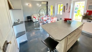 A modern kitchen with a central island, a dining area with a white table and red chairs, and a red sofa. - LUXURY APARTMENT - T4 DUPLEX - 100 M FROM ST CLAIR BEACH (Le Lavandou)