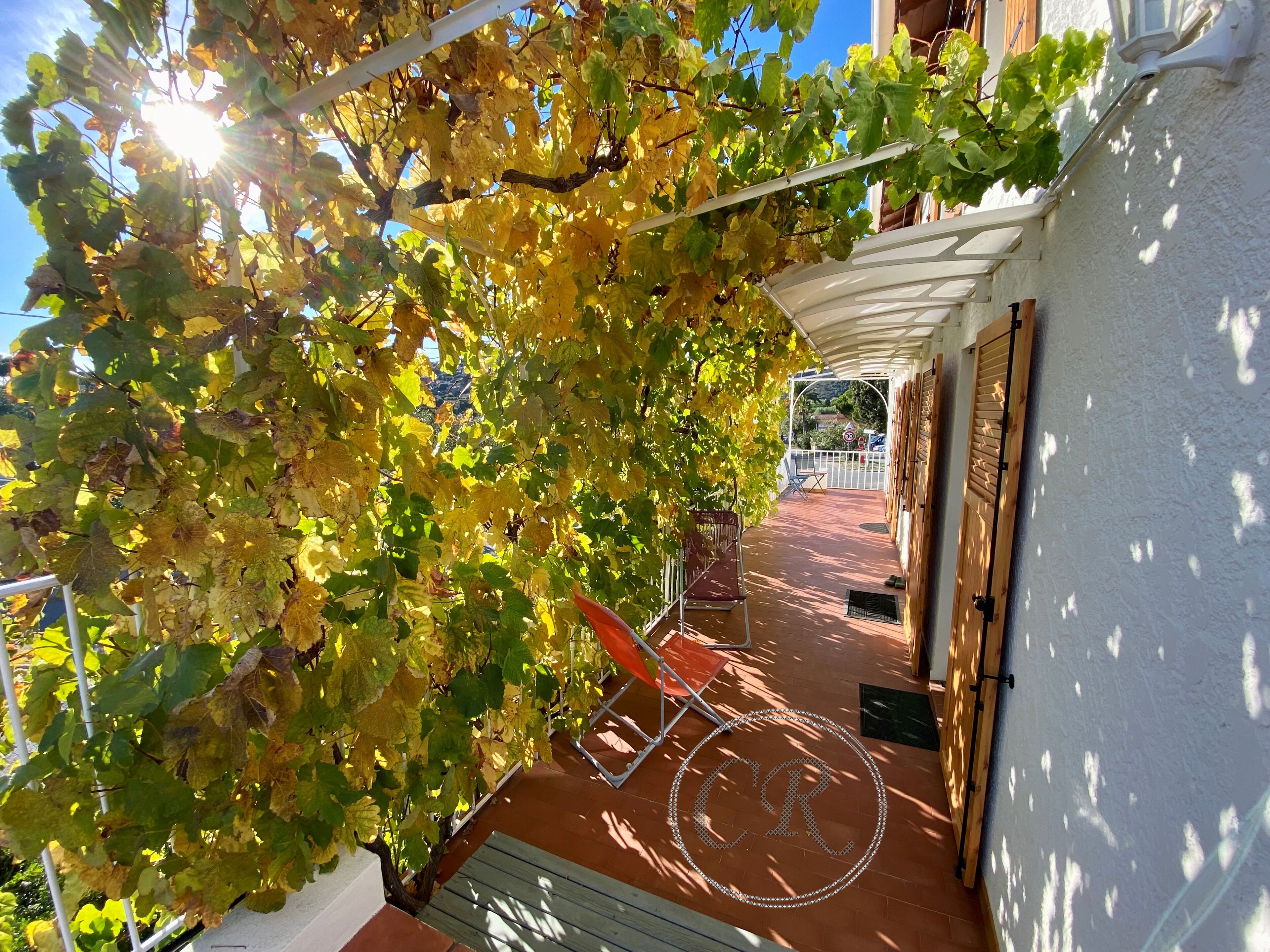 Een overdekt buitengebied met een pergola, een fiets en een zithoek.