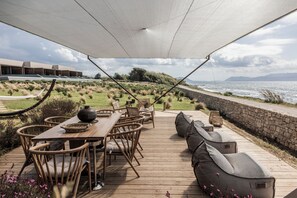 Relax on the outdoor deck with a sofa and dining area overlooking a beautifully landscaped garden and the sea.