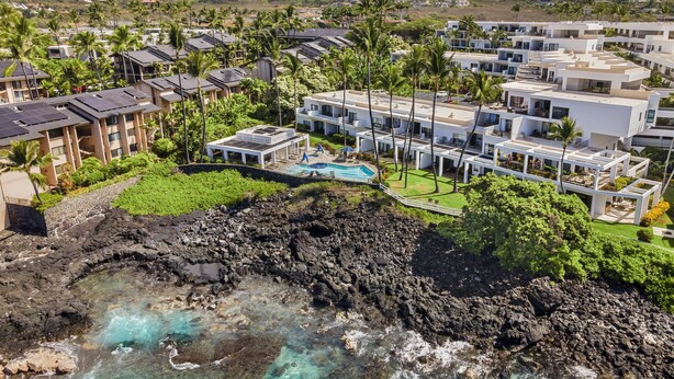 Et resort med moderne arkitektur, en swimmingpool og havudsigt.