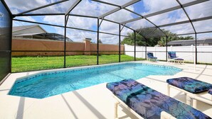 A covered swimming pool with lounge chairs and a view of a grassy yard. - Cloud 9 3/4 - Southern Pool, Privacy Fence! (Kissimmee)