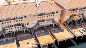 A multi-story hotel with balconies, outdoor seating areas, and a pool. - Spacious Waterfront Retreat | Balcony, Huge Deck & Views (Corpus Christi)