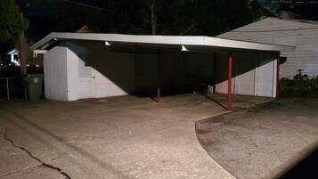 Un garage avec une allée couverte, une porte blanche et une poutre de soutien rouge.