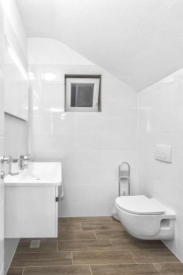Une salle de bain moderne avec un lavabo, un miroir et des toilettes, le tout de couleur blanche.