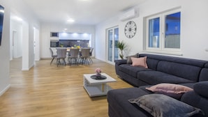 A modern living room with a grey sofa, a coffee table, and a dining area with chairs and a table. - Villa Antonia is near Trogir with a private pool (Marina)