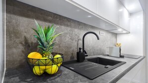 A modern kitchen with a grey countertop, a black sink, and a decorative bowl with fruits. - Villa Antonia is near Trogir with a private pool (Marina)