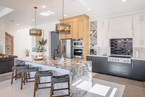 A modern kitchen with granite countertops, stainless steel appliances, and a central island with bar stools.