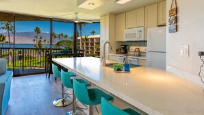 A modern kitchen with a large island, bar stools, and a view of the ocean.