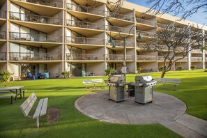 A multi-story building with balconies, a barbecue area, and outdoor seating.