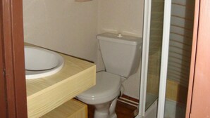 A small bathroom with a wooden cabinet, a toilet, and a sink. - 10m from resort center, 3rd floor, balcony, parking, tv, 20m², Pralognan-la-Vanoise (Pralognan-la-Vanoise)