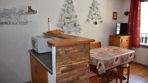 A compact kitchen with a wooden counter, a microwave, and a dining table with a checkered tablecloth.