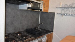 A compact kitchen with a stove, microwave, and a small sink.