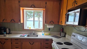 Una cucina con mobili in legno, una finestra vista mare, un fornello e un forno a microonde.