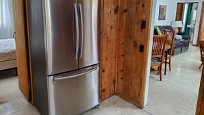 Una cucina moderna con frigorifero in acciaio inossidabile, rivestimenti in legno e un'area pranzo con tavolo e sedie.