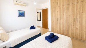 A hotel room with two beds, a wardrobe, and a painting on the wall. - Narcissos 'Nissi Beach' apartment C12 (Ayia Napa)